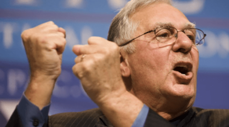 Image: An enthusiastic elderly man with glasses clenching his fists in a gesture of victory or passion, speaking at a FreedomWorks podium with blurred text in the background. -- D.C. Douglas