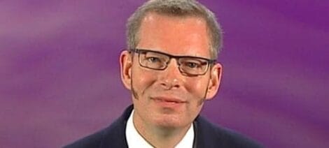 Image: A middle-aged man with glasses, wearing a dark suit, smiles gently against a purple background in an open letter. -- D.C. Douglas