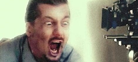 Image: Close-up of a man with a shocked expression, his mouth wide open as if yelling or surprised. The background is blurred with hints of mechanical details, perfect for a social media post. -- D.C. Douglas