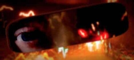 Image: A close-up of a human eye reflected in a car's rearview mirror, with flames and bright light blurred in the background, creating a dramatic and intense scene reminiscent of "The Crooked -- D.C. Douglas