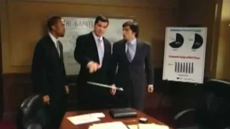 Three men in business suits discussing in a meeting room with a presentation board in the background.