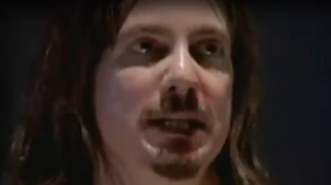 Close-up image of a man with long hair and a goatee, looking directly at the camera.