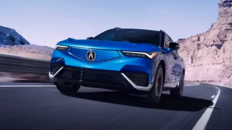 Blue Acura SUV driving on a road with a mountainous background.