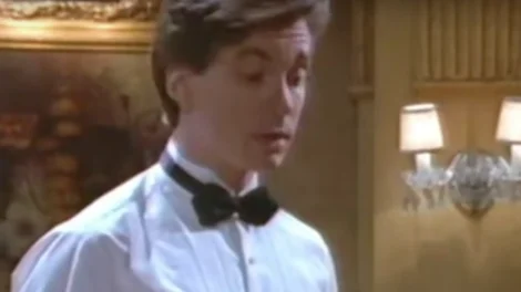 A young man wearing a white shirt and black bow tie, looking slightly surprised or confused.