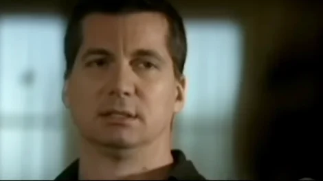 A man with short dark hair and a serious expression, looking slightly to the side in a neutral setting.