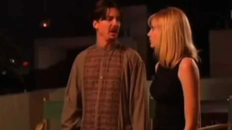 A man wearing a patterned shirt and a woman in a black top talking to each other.