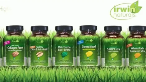 Five bottles of Irwin Naturals dietary supplements arranged in a row on a grassy background.
