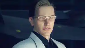A man wearing a light-colored suit and glasses, looking directly at the camera.