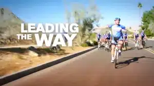 Top 5 Best Commercials Of 2025 | D.c. Douglas A cyclist in blue attire riding on a road with other cyclists in the background.