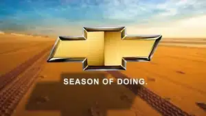 Voice Over: Radio, Streaming, &Amp; Podcast Commercials | D.c. Douglas Chevrolet logo in gold with the slogan 'Season of Doing' below it on a sandy background.