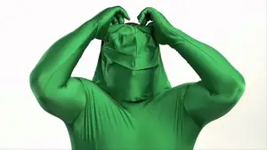 Navigating The Intricacies Of Medical Narration: From Corporate Videos To Patient Education | D.c. Douglas Person wearing a green full-body suit with a hood, adjusting the fabric on their head.