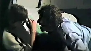 Two individuals interacting closely, one holding a camera while the other leans in during a conversation.