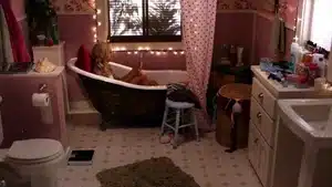 A vintage-style bathtub in a bathroom with decorative lights and a window.