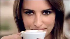 Top 5 Best Commercials Of 2025 | D.c. Douglas Woman with brown hair holding a white coffee cup close to her face, looking directly at the camera.