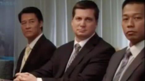 Three men in business suits sitting at a conference table during a meeting.