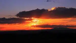 Vibrant sunset with orange and purple hues illuminating the sky and clouds.