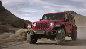 Top 5 Best Commercials Of 2025 | D.c. Douglas Red Jeep Wrangler driving on a dirt road in a rugged landscape with rocky terrain.
