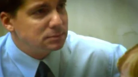 Close-up of a man wearing a light blue dress shirt and a tie, looking intently at something off-camera.