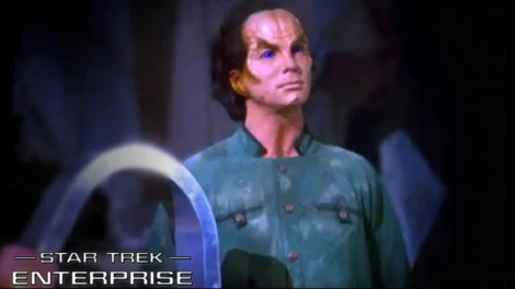 A character from Star Trek Enterprise wearing a green uniform with distinctive facial features.
