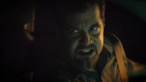 Close-up of a man displaying an intense expression while seated in a vehicle.